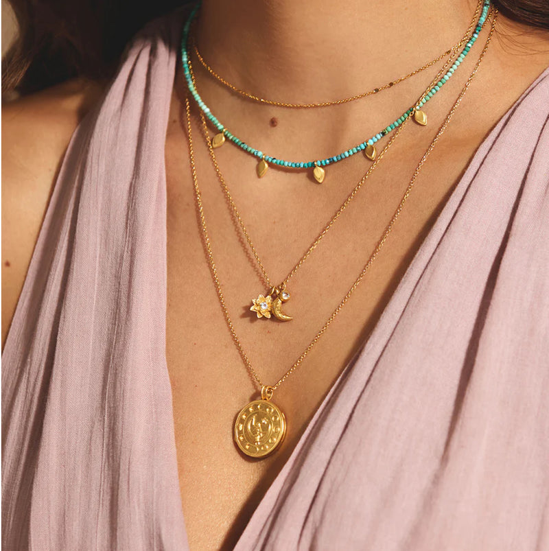 Protected by the goddess moon, we are free to transform into our most authentic selves. An 18kt gold plated necklace is adorned with a lotus flower, a crescent moon, and a white topaz star, inspiring new beginnings, offering protection and goddess energy,