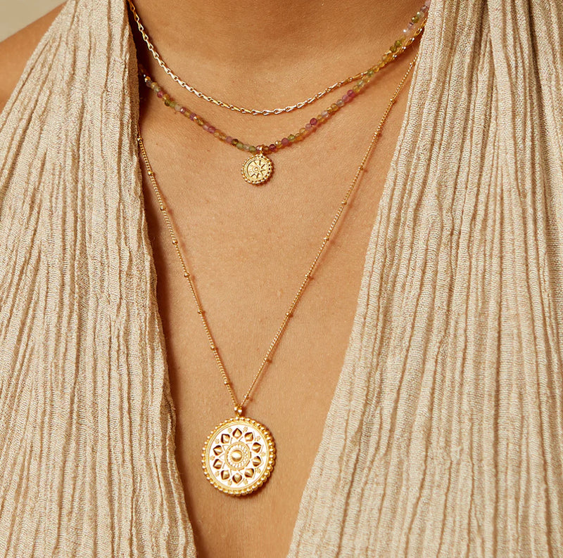 This is an invitation to journey home to yourself, to tend to the brilliance of your inner light. An 18kt gold plate necklace gleams with an intricate mandala pendant. Designed to reflect the multi-layered petals of the lotus flower, a symbol of new begin